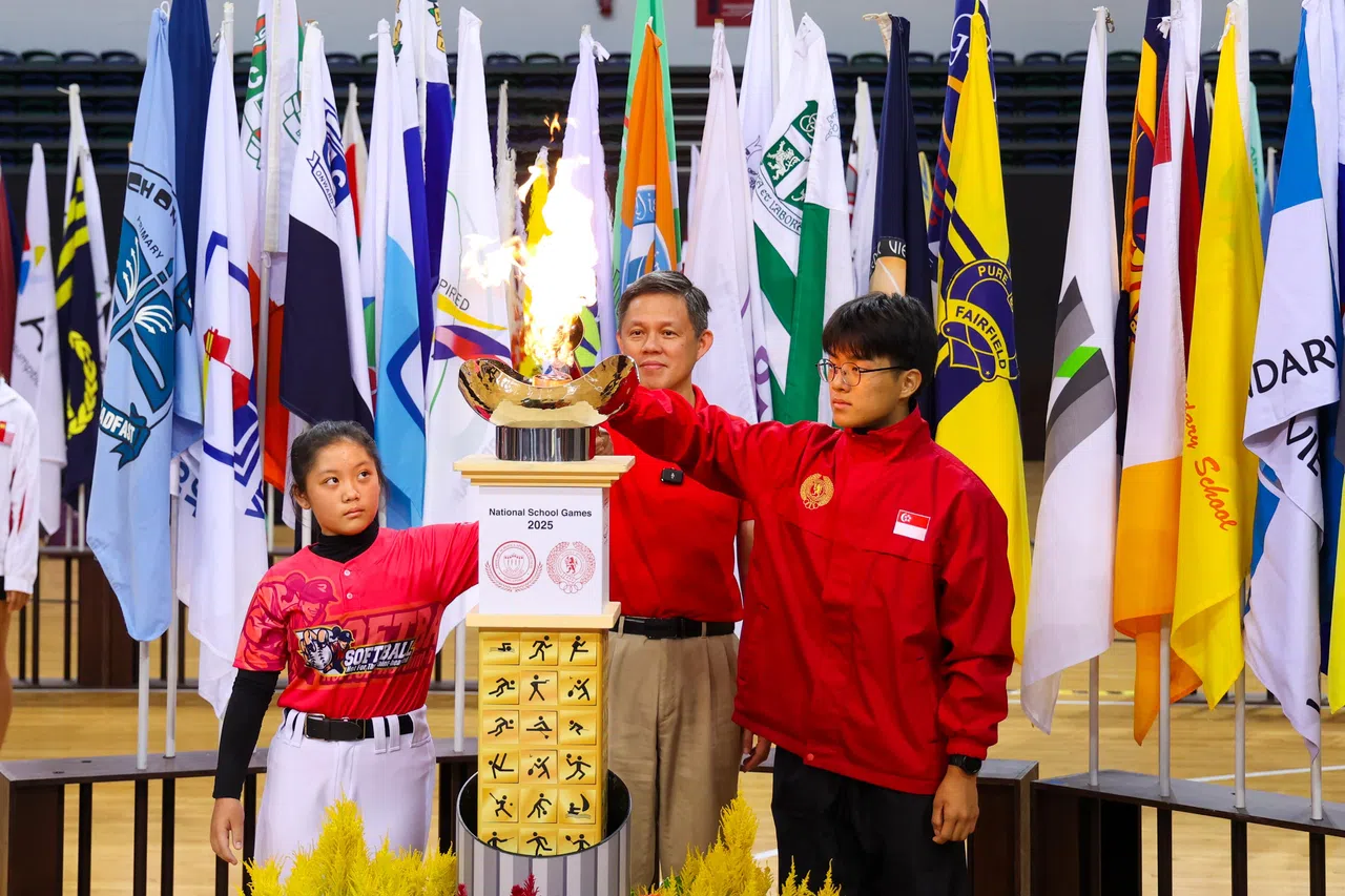 教育部长陈振声（中）与来自孺廊小学的王信玲（左）和国大数理中学的成锐晙（右）两名火炬手，一起点燃全国校际运动会的火炬。（林明顺摄）