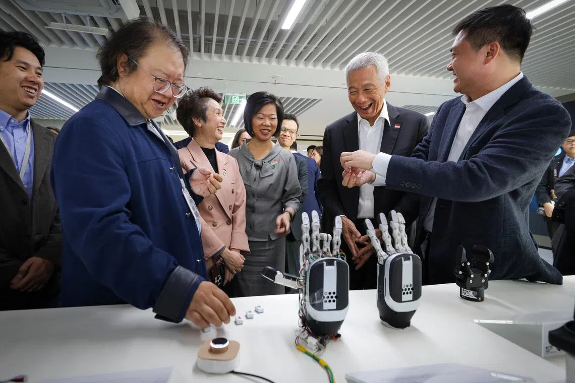 李资政（右二）星期四（11月28日）在上海参访智元机器人。外交部兼国家发展部高级政务部长沈颖（右三）和贸工部兼文化、社区及青年部高级政务部长刘燕玲（右四）陪同参访。智元机器人创始人邓泰华（右一）及联合创始人闫维新（左一）为李资政讲解。根据智元机器人官网，上海智元新创技术公司成立于2023年2月，是一家致力于以AI+机器人的融合创新、打造世界级领先的具身智能机器人产品及应用生态的企业。（数码发展及新闻部）