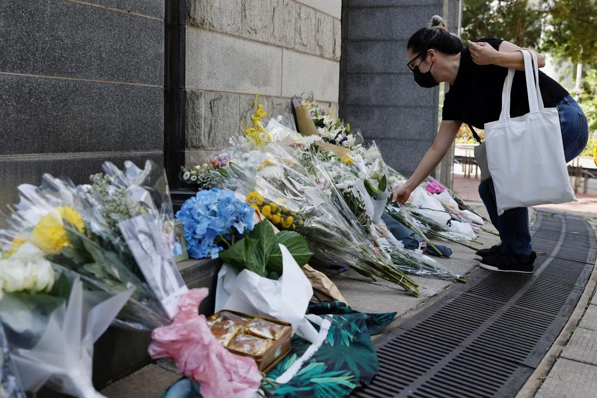 一名女子星期五（9月9日）在英国驻港总领事馆外摆放花束，向逝世的英女王伊丽莎白二世致哀。（路透社）