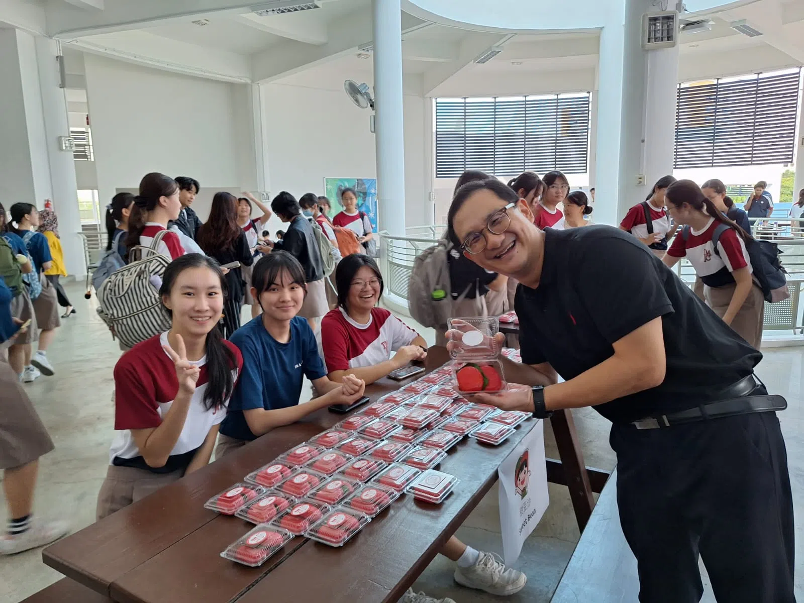 活动结束后，每个学生都获派两个寓意吉祥长寿的红龟粿。图为淡美初院院长冼健豪（右）与派发红龟粿的学生合影。（淡滨尼美廉初级学院提供）