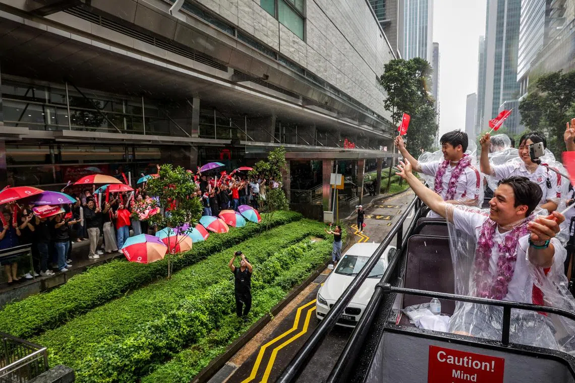 尽管下着雨，但民众热情不减，为选手们摇旗欢呼。（叶振忠摄）