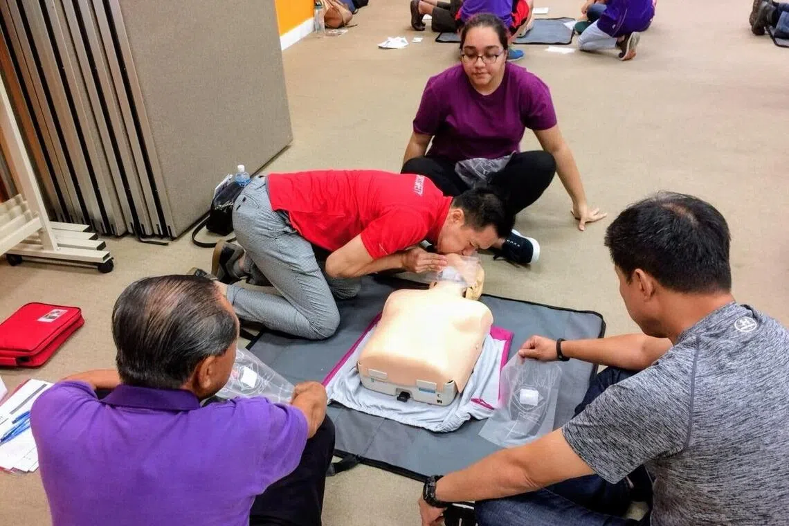 平日里，卓国强（红衣）的主业是一名急救课程讲师。图为他在示范心肺复苏步骤，教导受训人员在“黄金三分钟”内抢救生命的方法。（受访者提供）