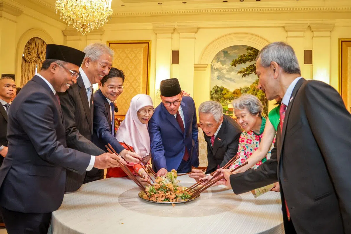 安华伉俪（左四、左五）1月30日访问新加坡时，新马领导人在李显龙总理（右四）设的午宴上一起捞鱼生。（叶振忠摄）