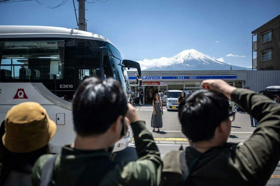 游客在山梨县富士河口湖镇一个热门拍照地点拍摄富士山。（法新社）