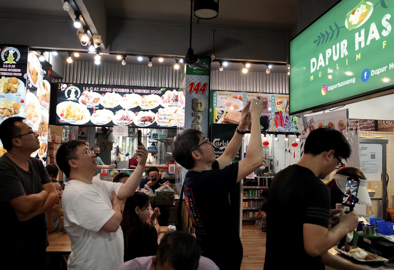 球迷们在哈山的档口前，一边排队，一边拍照留念。（卓舒畅摄）