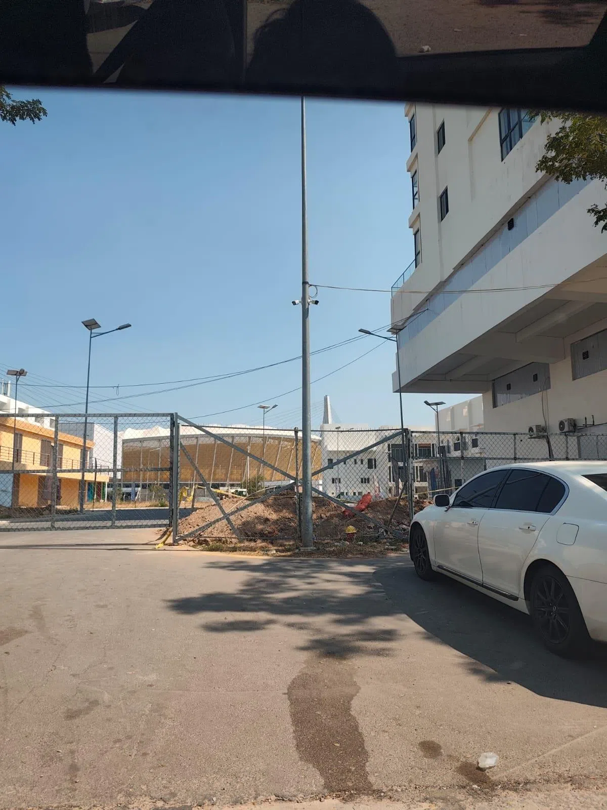 柬埔寨金边电诈园区入口围着铁篱笆，将园区与外界隔绝成两个世界。这个园区位于2023年东运会体育场附近。（受访者提供）