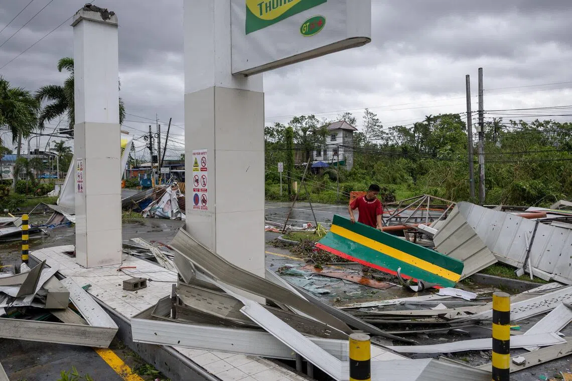 11月10日，菲律宾新比斯开省一名工人在台风凤凰过境后清理受损的加油站残骸。（路透社）