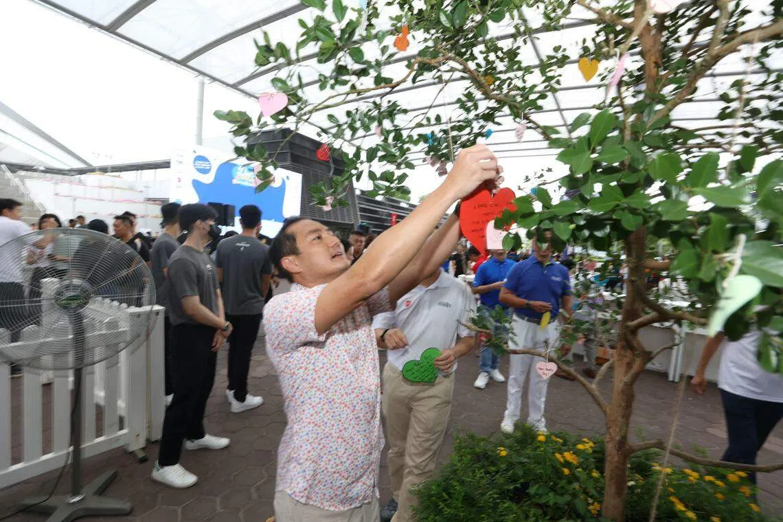 通讯及新闻部兼国家发展部高级政务部长陈杰豪出席“爸爸外出日”活动时，将对父亲的无尽感激之情写在心形纸张上，再将纸张挂上草莓番石榴树。（蔡家增摄）