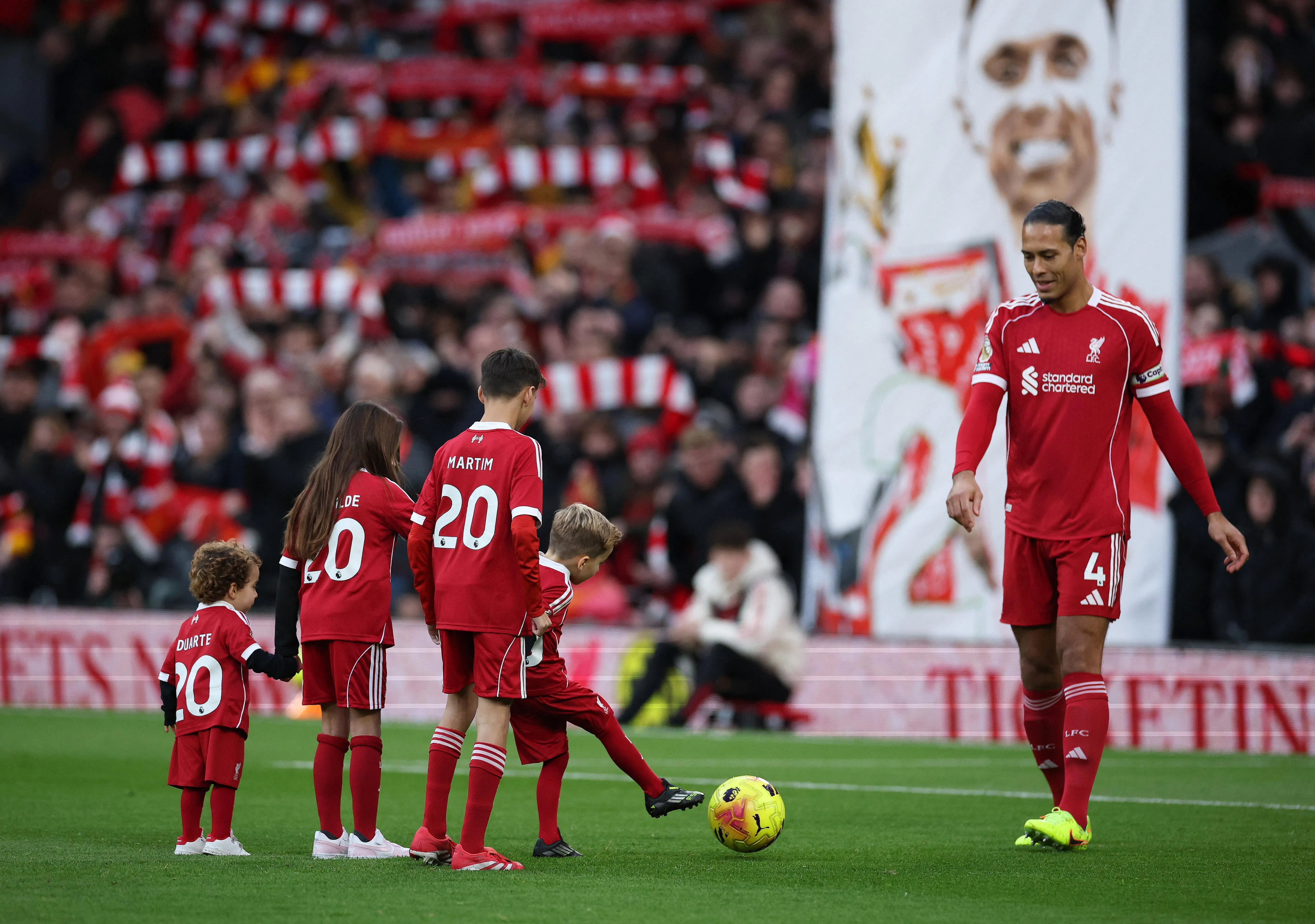 在上星期六对阵狼队赛前，红军队长兼后卫范戴克（右）与包括若塔两个儿子在内的小球员互动，背景里是巨大的若塔肖像。（路透社）