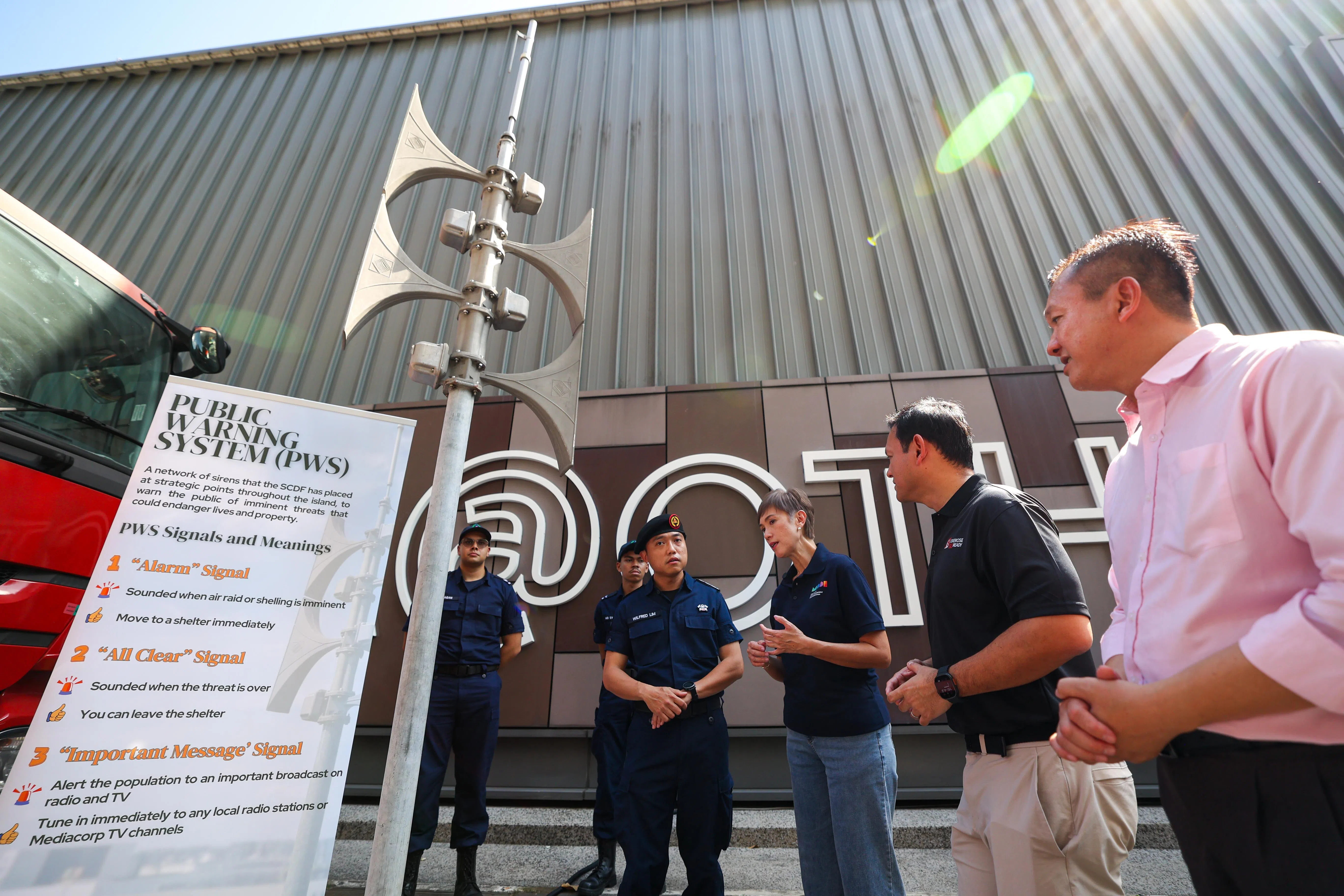 数码发展及新闻部长杨莉明（右三）在启动仪式后，向民防部队人员了解公众警报系统的操作细节。右二为国防部兼永续发展与环境部高级政务部长扎吉哈，右一为政府国会国防与外交委员会成员李宏壮。（林明顺摄）