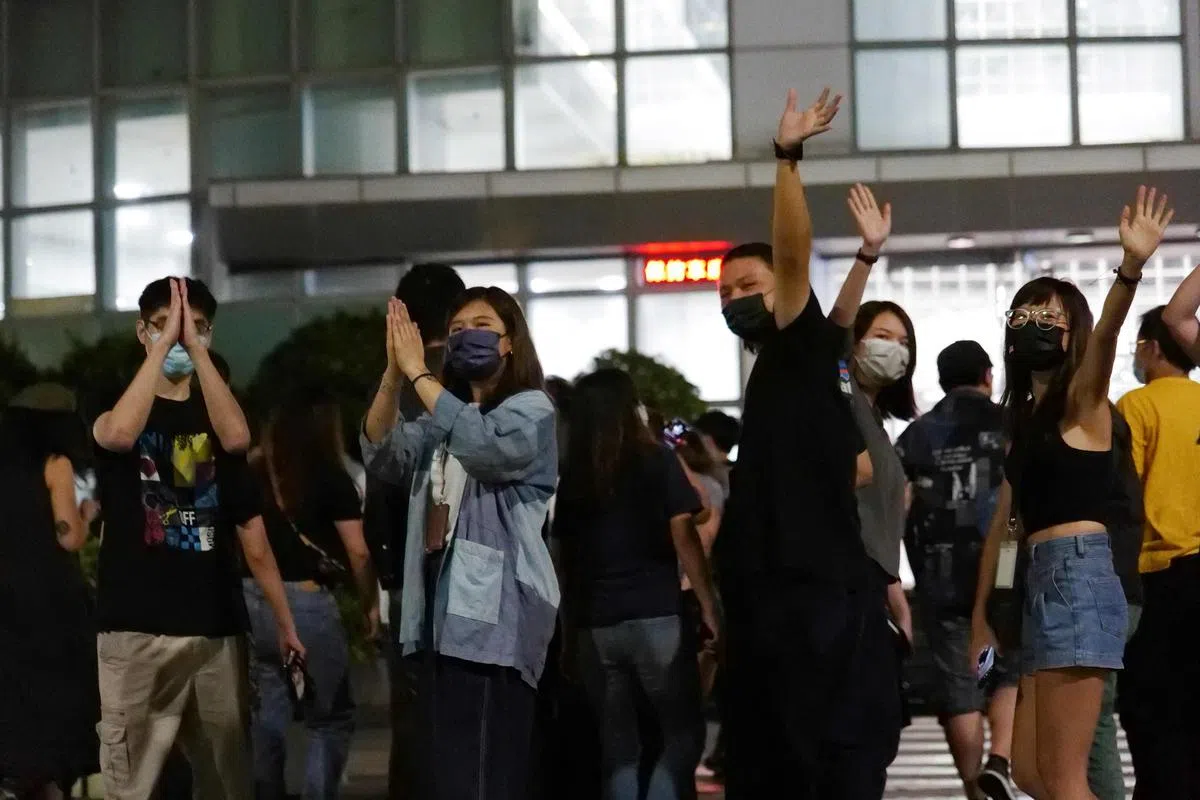 《苹果日报》记者在办公楼外，向支持者挥手致谢。（法新社）