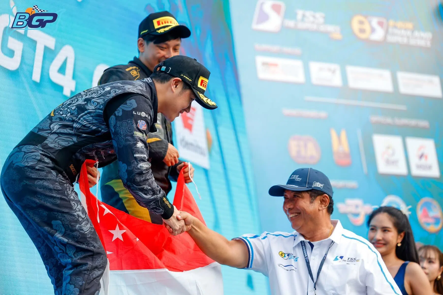 洪士渊（左前）和何崇义（左后）在第三轮比赛手持新加坡国旗登上领奖台。（泰国房车超级系列赛提供）