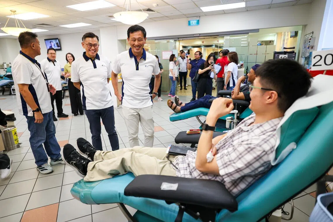 社会政策统筹部长兼保健卫生部长王乙康（中）星期三（4月15日）出席全国捐血计划80周年庆祝活动，探访在卫生科学局血库（Bloodbank@HSA）捐血的公众。（林明顺摄）