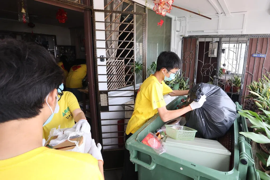 学生先将屋内的囤积物搬到屋外，让屋主挑出不能丢弃的东西，其余则分类放入白色和黑色垃圾袋，随后动手进行大扫除。（邬福梁摄）