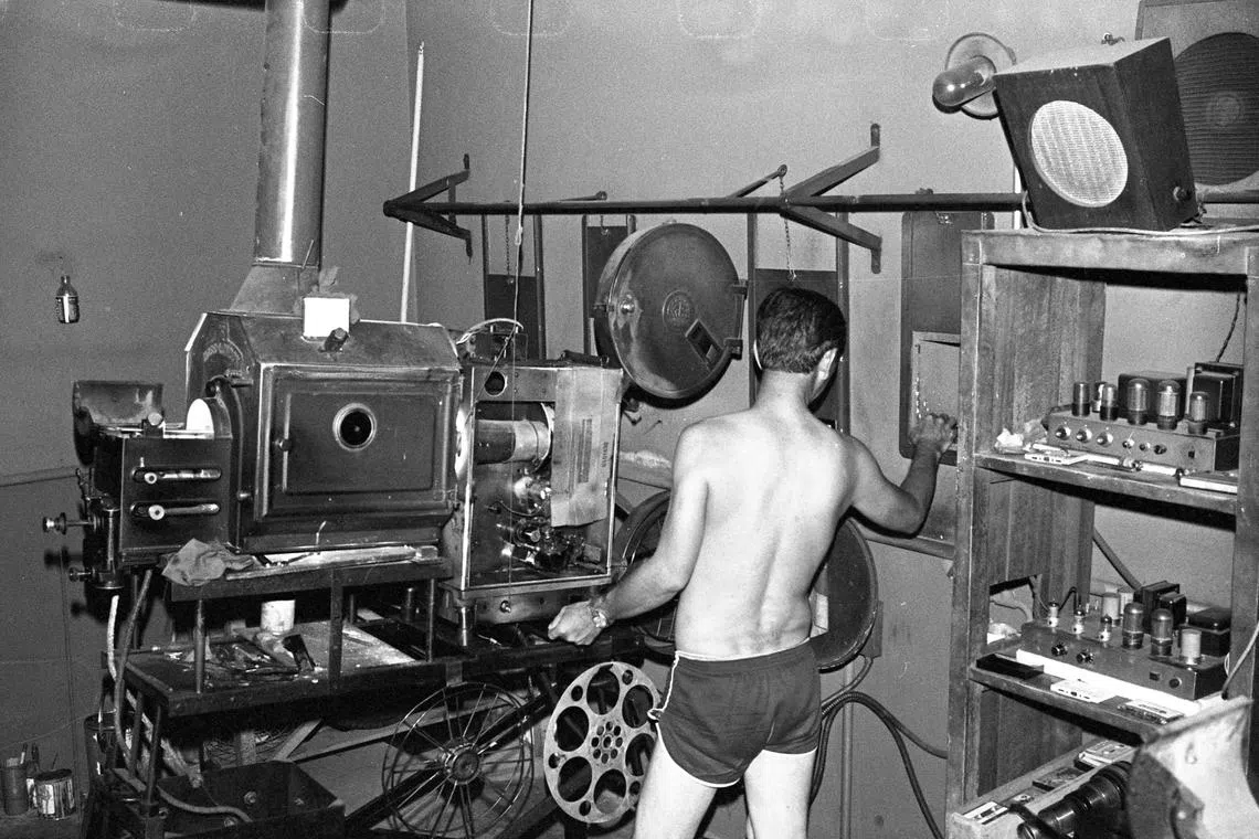 1984年荷兰村的荣华露天戏院，男员工在银幕后操作笨重放映机，确保影片顺利播放。（档案照片）