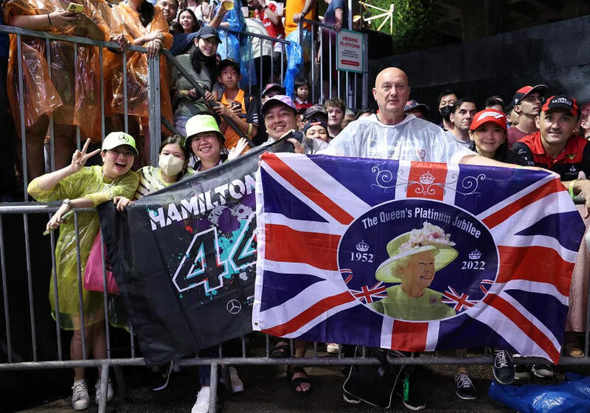 车迷拿着印有刚与世长辞的英女王照片的英国国旗和哈密尔顿名字的横幅支持英国车手。（张思庆摄）