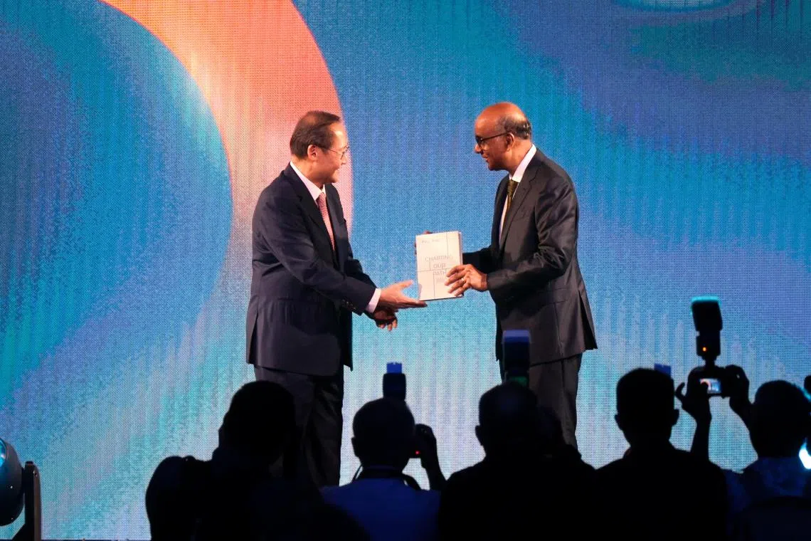 人力部长兼贸工部第二部长陈诗龙医生（左）将人力部周年庆纪念书交到尚达曼总统手上。尚达曼在2011年至2012年之间出任人力部长。（张俊杰摄）