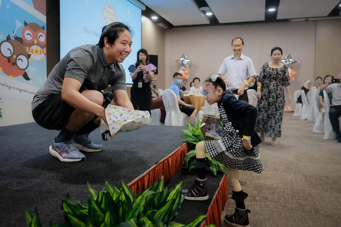 骨髓捐赠受益者何雯晴星期六在比达达利民众俱乐部，与捐赠者林维杰见面。她忍着脚痛慢慢走上台，为救命恩人递上一张摄于2019年10月17日她接受骨髓移植后躺在病床上的照片，表达感谢。站在何雯晴后方的是她的父母何松安和吴秀玲。（海峡时报）