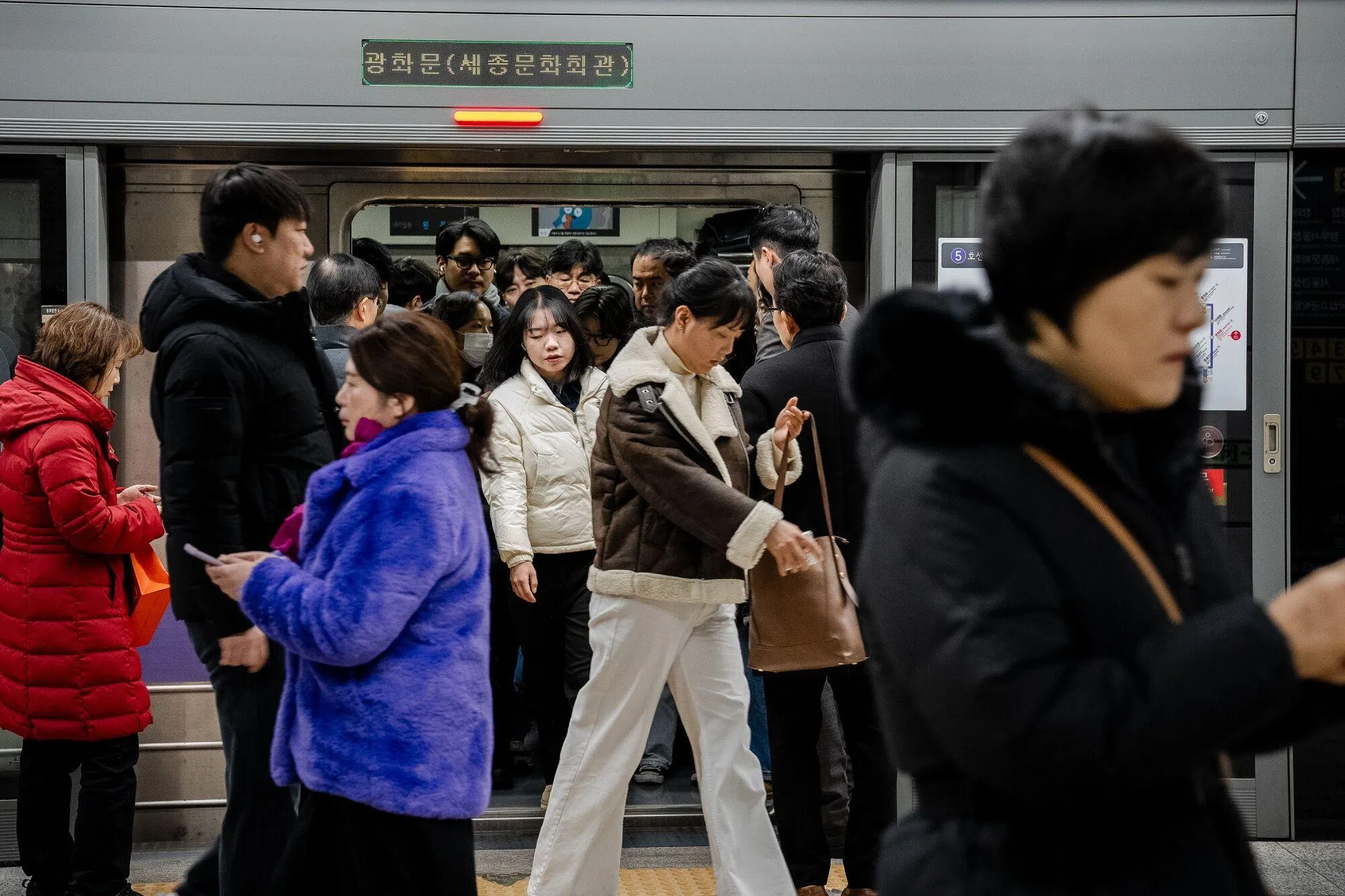 韩国首尔星期三（12月4日）早上的地铁像往常一样拥挤，乘客在地铁列车到站后下车前往公司上班。（彭博社）