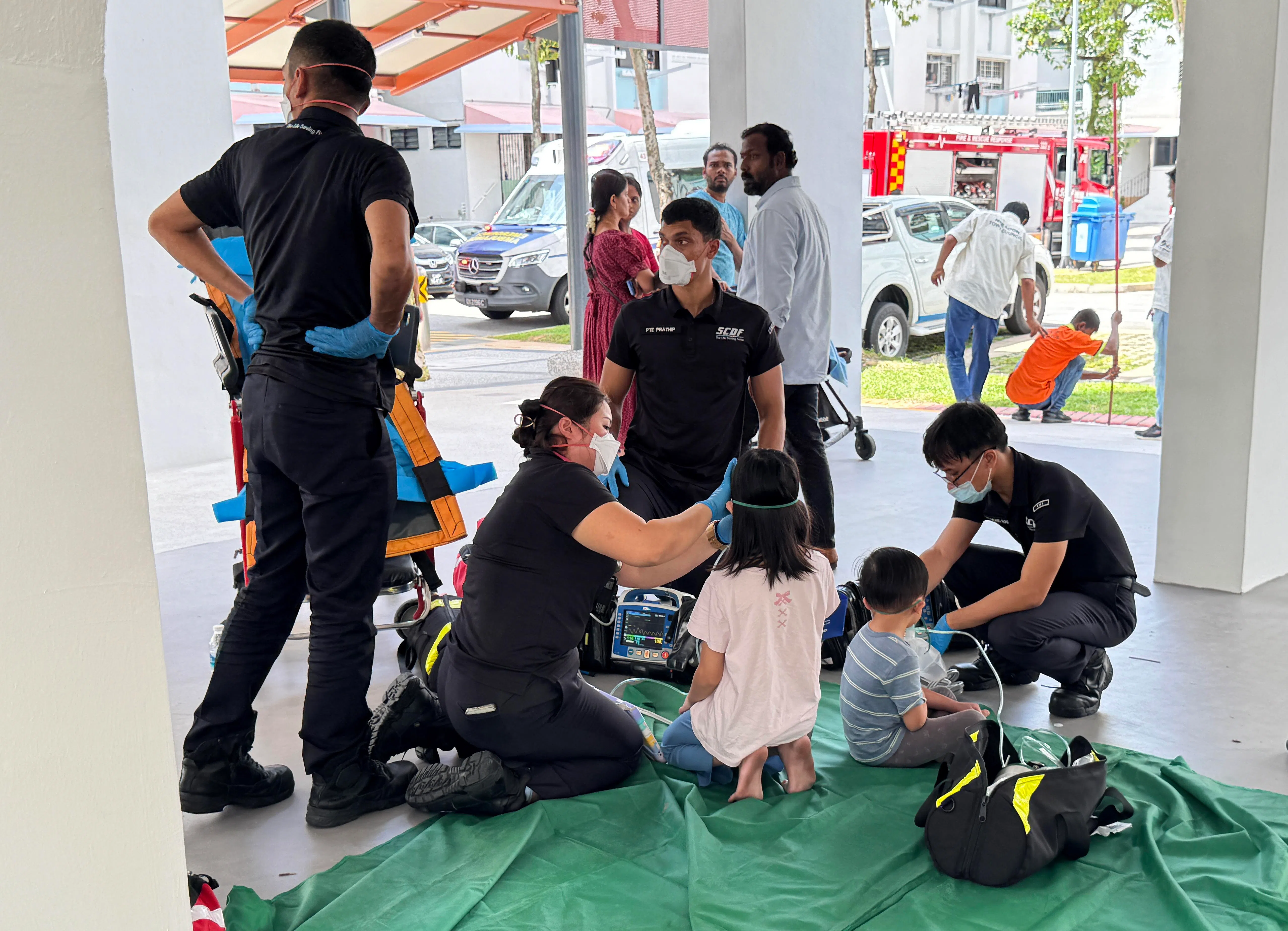 一些居民疏散到组屋楼，有些戴着氧气罩，接受到场医护人员的援助，其中包括两名孩童。（何炳耀摄）