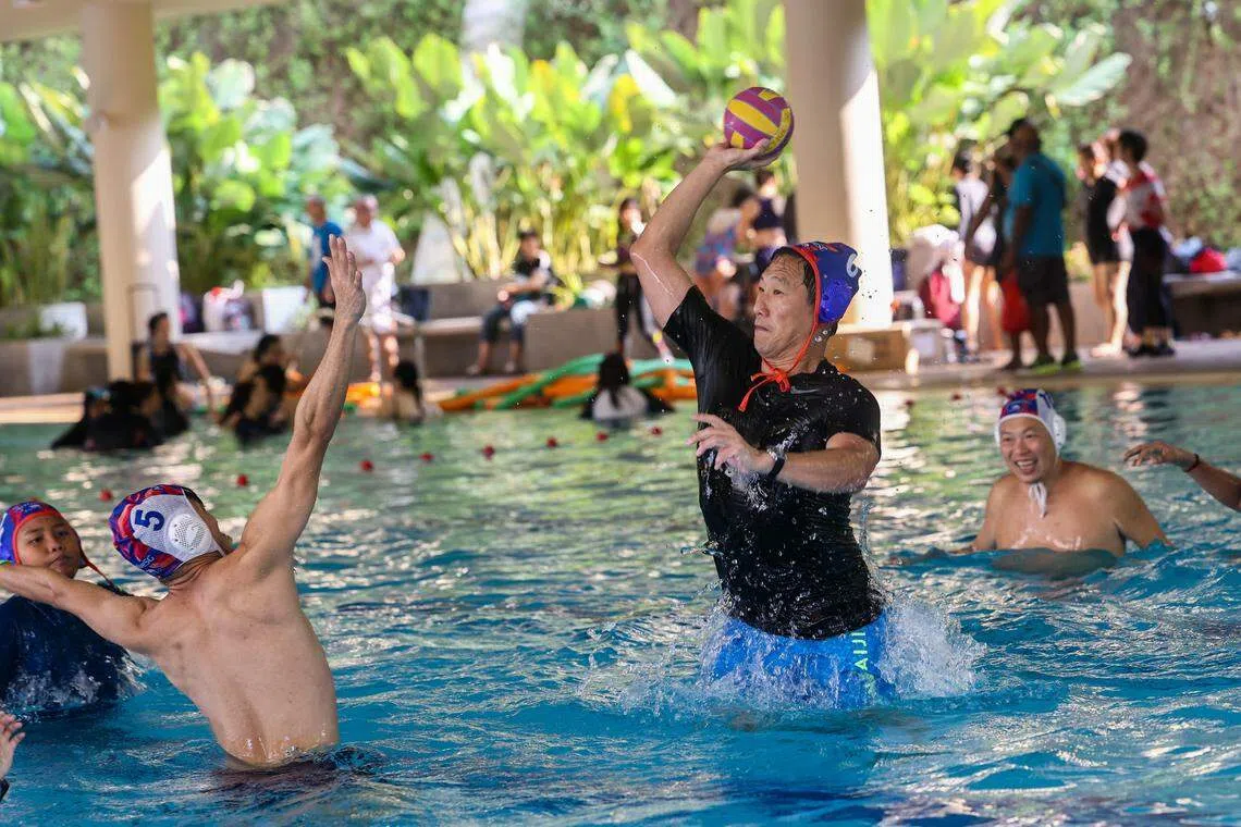 卫生部长王乙康（手握球者）星期天为武吉坎贝拉综合中心的ActiveSG游泳池设施主持开幕后，与居民一起在泳池玩简化式水球“Flippa Ball”。（陈斌勤摄）