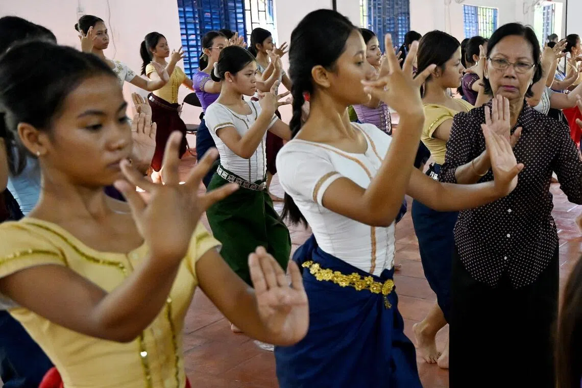 任教于金边艺术中学的高棉古典舞大师边延（右）细心纠正学员的手势和姿态。（法新社）