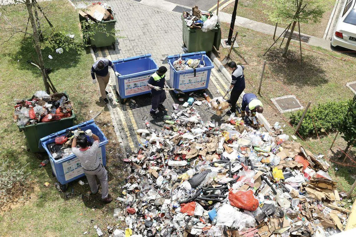 垃圾车里的垃圾着火后被倾倒地上，灭火后再由工人将这些垃圾转移到另外一辆垃圾收集车上。（邬福梁摄 ）