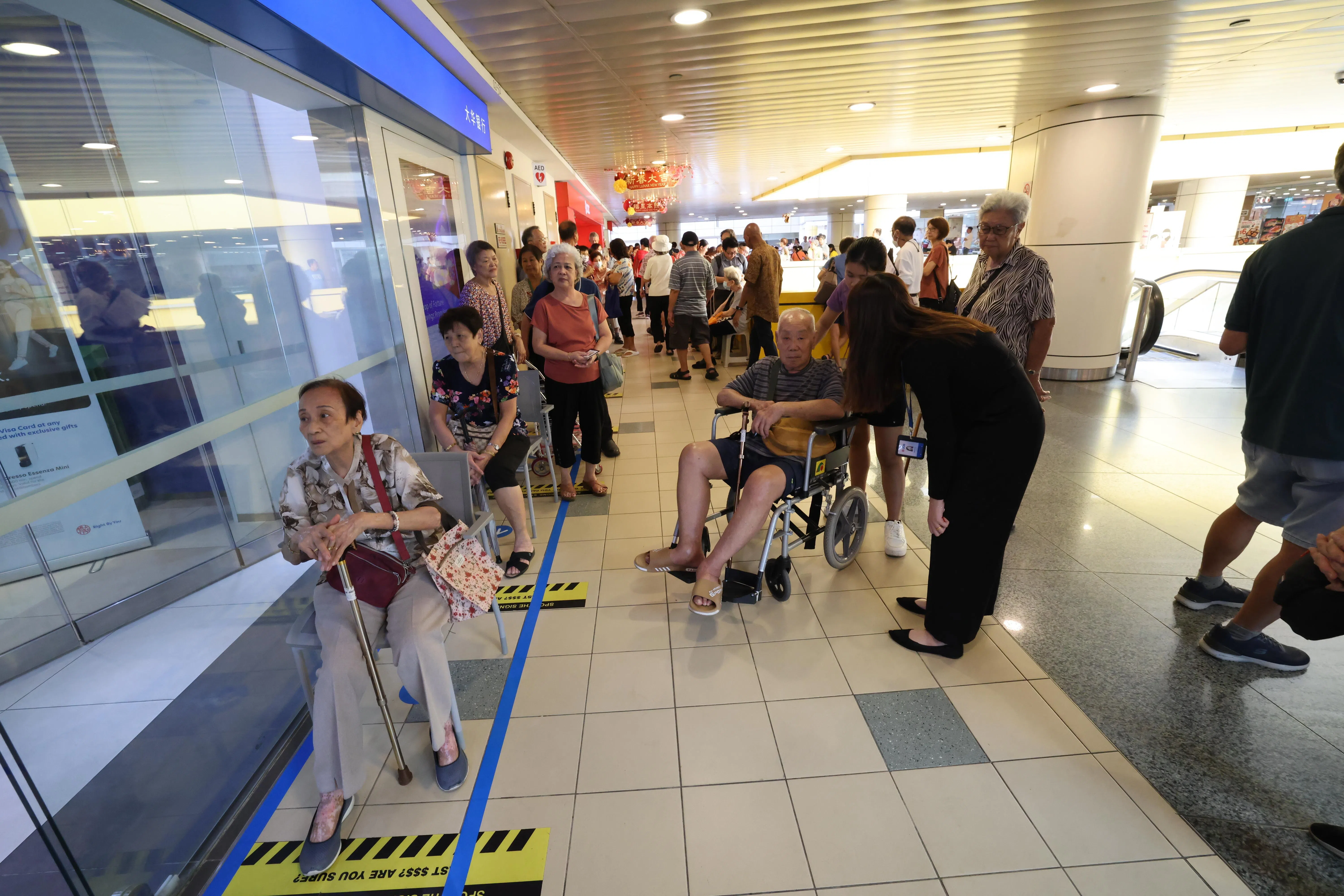 大华银行大巴窑中心门店上午10时30分开门前，聚集了大批排队领取新钞的年长者，他们不必上网预约，就可到银行柜台提取新钞。（梁麒麟摄）