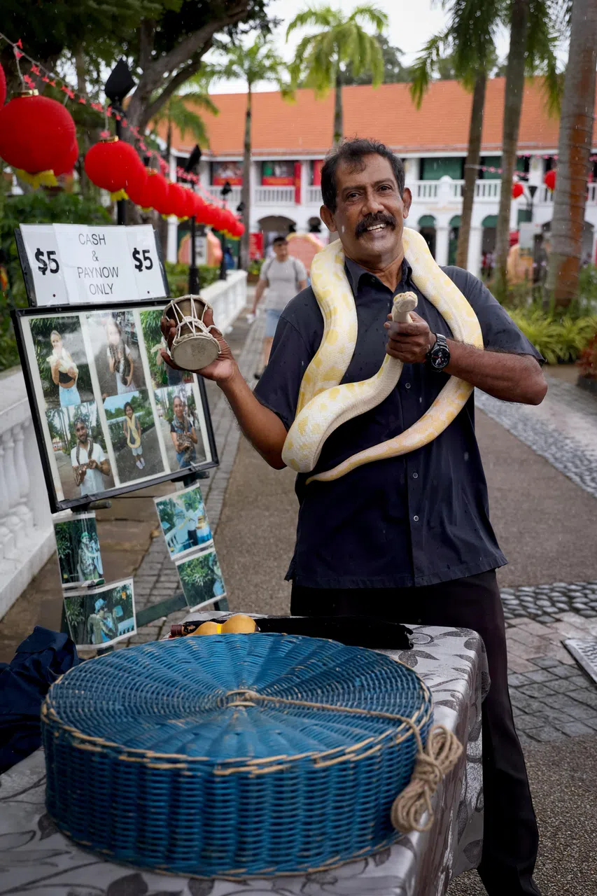 闲暇时间，尤索夫会在圣淘沙岛的SkyHelix附近出摊与游客拍照。（龙国雄摄）