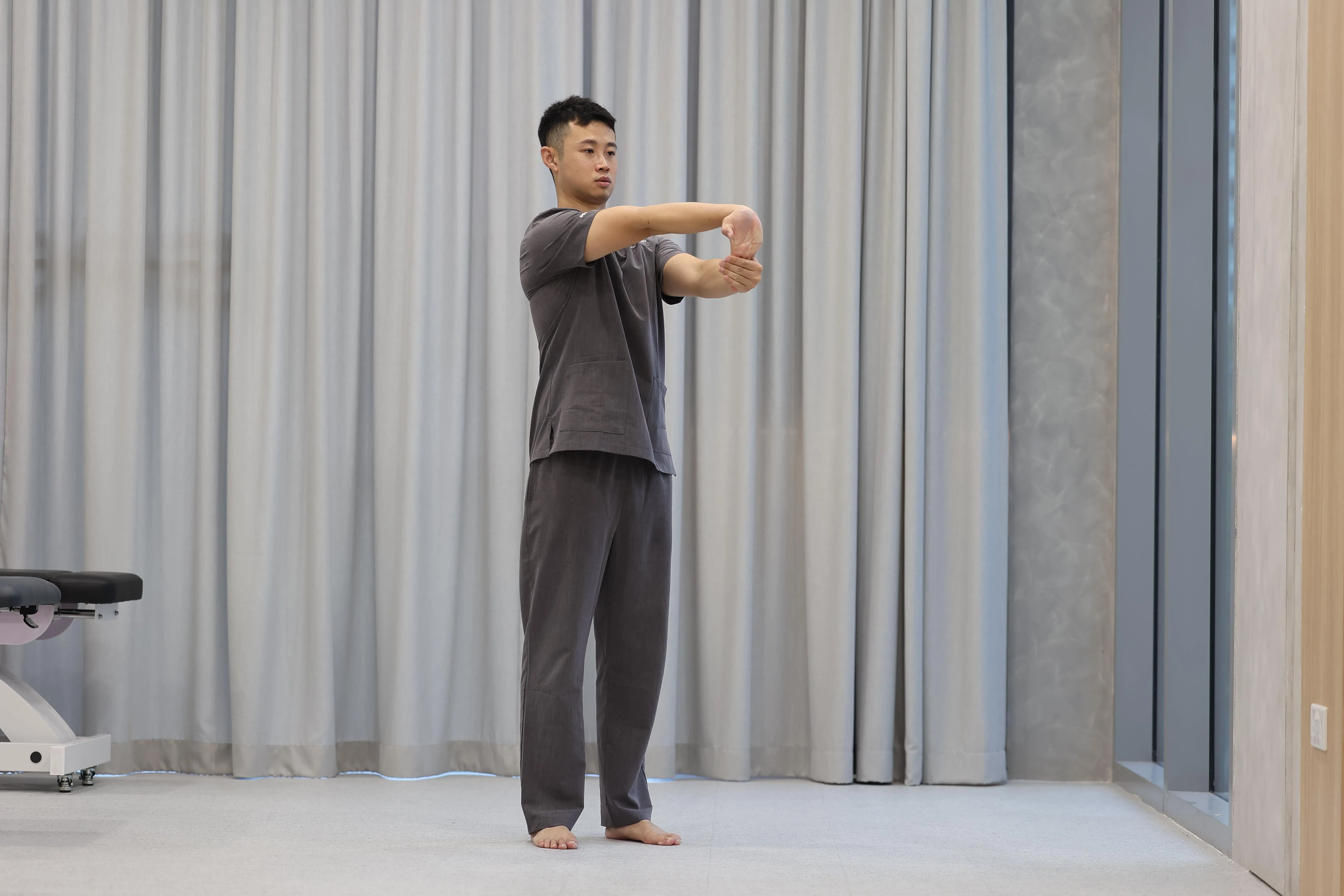 左手抓住右手四根手指，右手臂向前伸直，掌根向前推，手指向下。（关俊威摄）