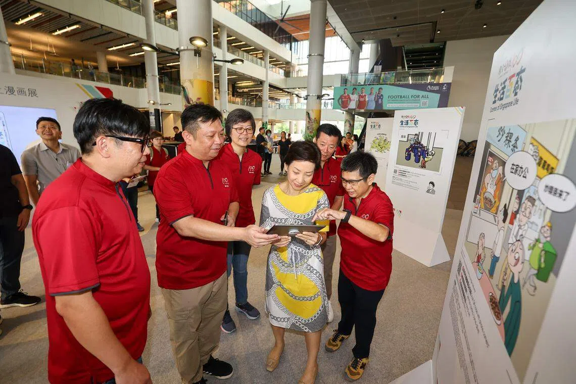 “生活百态”漫画展开幕仪式在榜鹅综合社区中心举行。图为永续发展与环境部长傅海燕（右三）与早报视觉部高级美术员张进培（左起）、视觉部副主任（动态设计)叶伟成、新报业媒体华文媒体集团社长李慧玲、《联合早报》总编辑吴新迪和执行总编辑韩咏梅一同参观展览并体验线上漫画展。（陈渊庄摄）