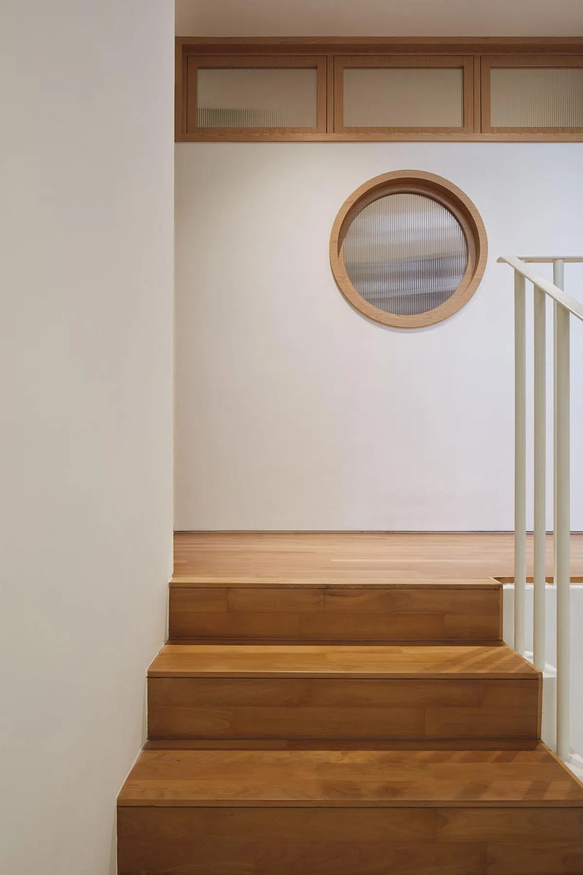 一扇轮船风格的浑圆玻璃窗嵌入楼梯间的墙，给人视觉上的惊喜。