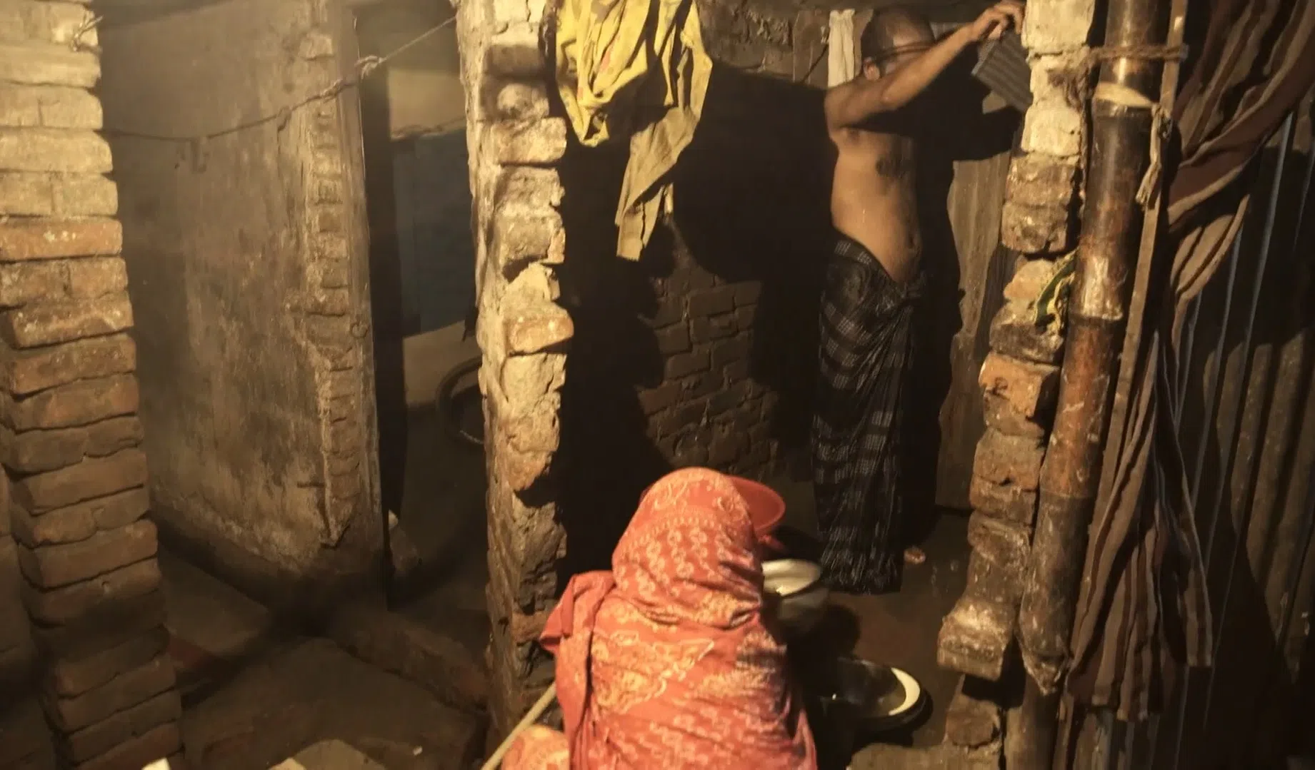 孟加拉贫民窟里的厨房就在厕所外，妇女都在地上处理食材。（视频截图）