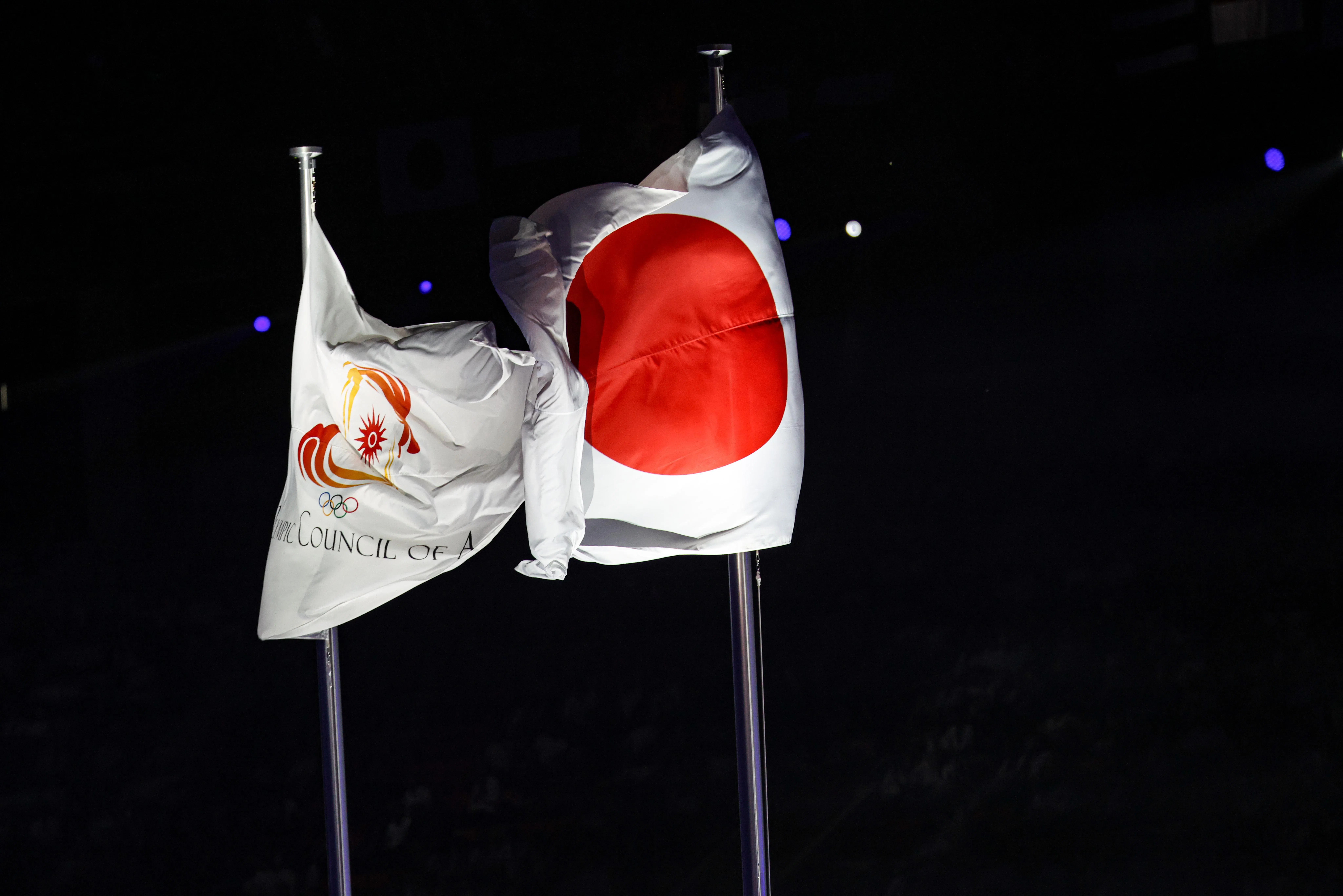 日本国旗和亚洲奥委会旗帜在旗杆上飘扬。（关俊威摄）