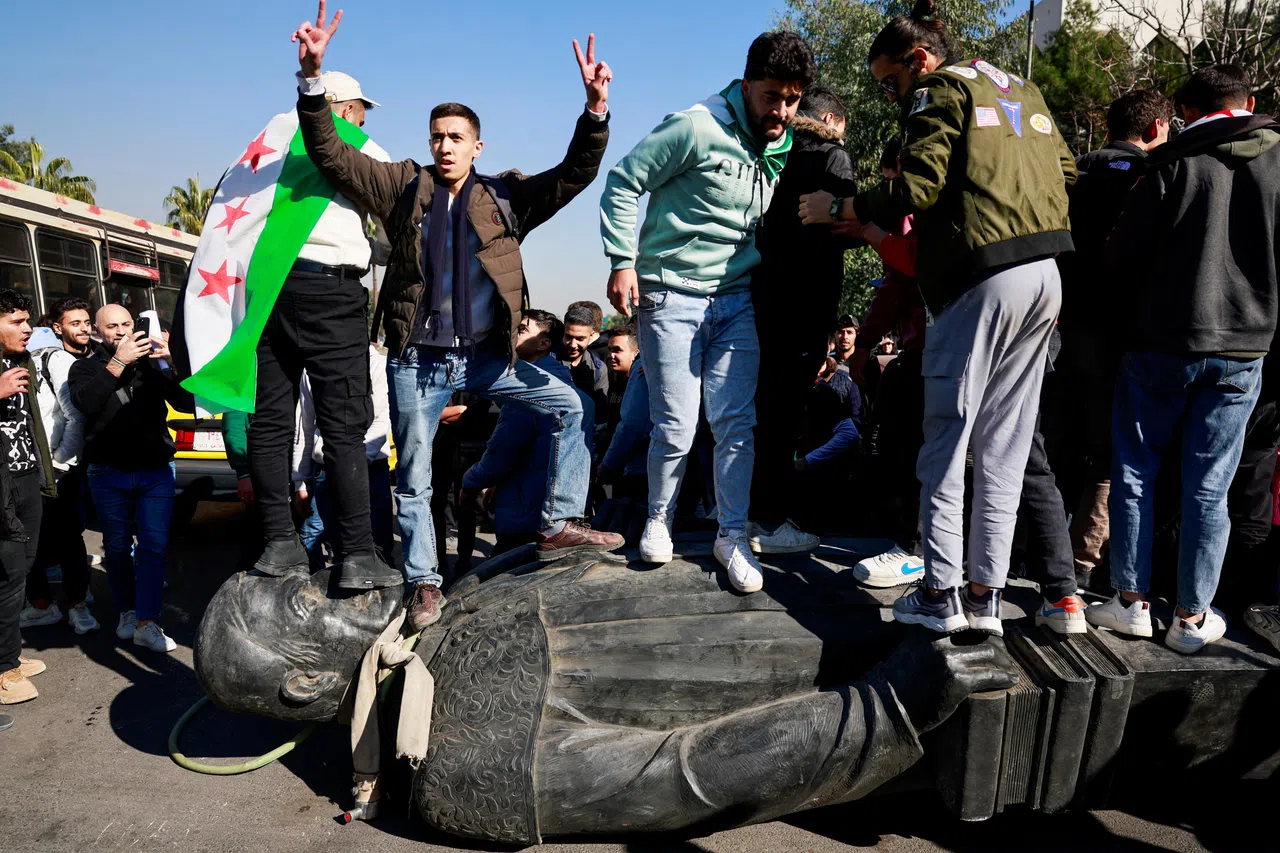 阿萨德倒台后，叙利亚各地民众推倒他和他父亲哈菲兹的塑像。大马士革大学的学生星期天（12月15日）践踏一座哈菲兹塑像上，欢庆阿萨德政权倒台。（路透社）