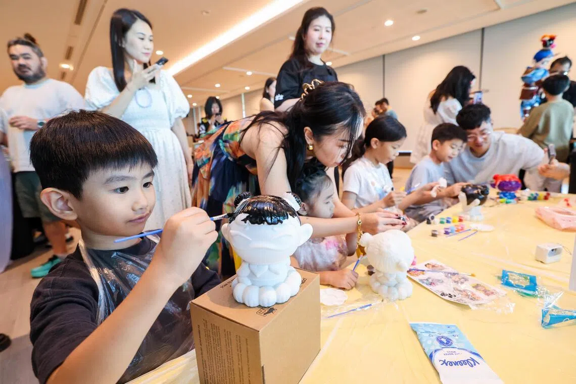 在星期六的儿童文化节预览会上，猴纸剧坊的成员在现场引导小朋友用油漆给哪吒模型上色，并尝试操作传统的杖头木偶。（陈斌勤摄）