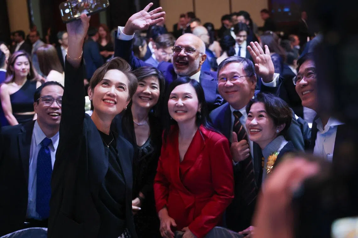 数码发展及新闻部长杨莉明（前排左）和新加坡电脑学会会长林镁绢（中，红衣者）等人在晚宴上合照。（张俊杰摄）