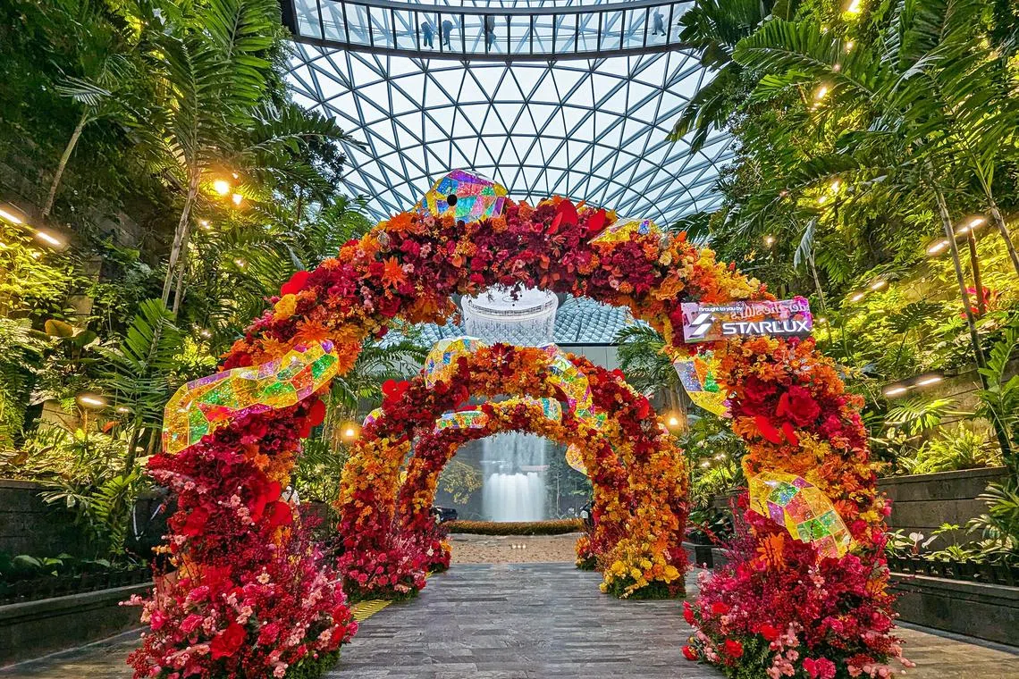 由粉橘黄三色花点缀，星耀樟宜雨漩涡前的新春拱门格外亮眼。（星耀樟宜机场发展公司提供）