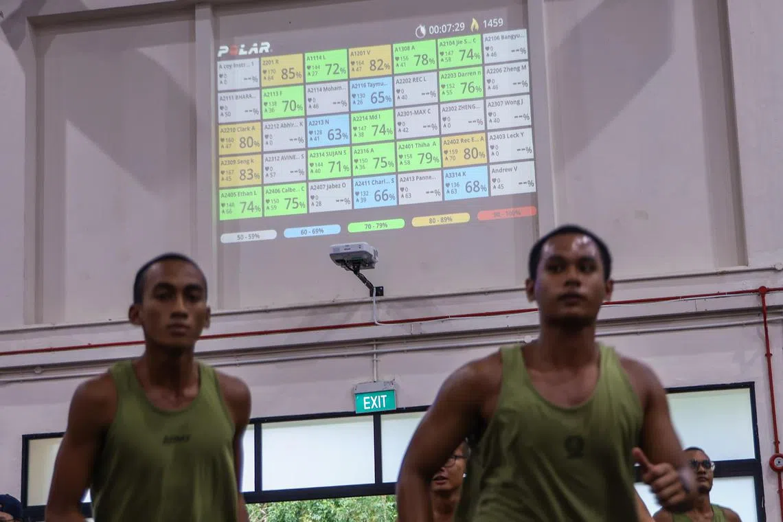 基本军训中心借助体能穿戴设备，追踪每个新兵的心率、训练负荷、睡眠周期与饮食情况，从而量身制定训练计划。图为穿戴设备的新兵接受体能训练，墙上投影显示他们的心率区间。（白艳琳摄）