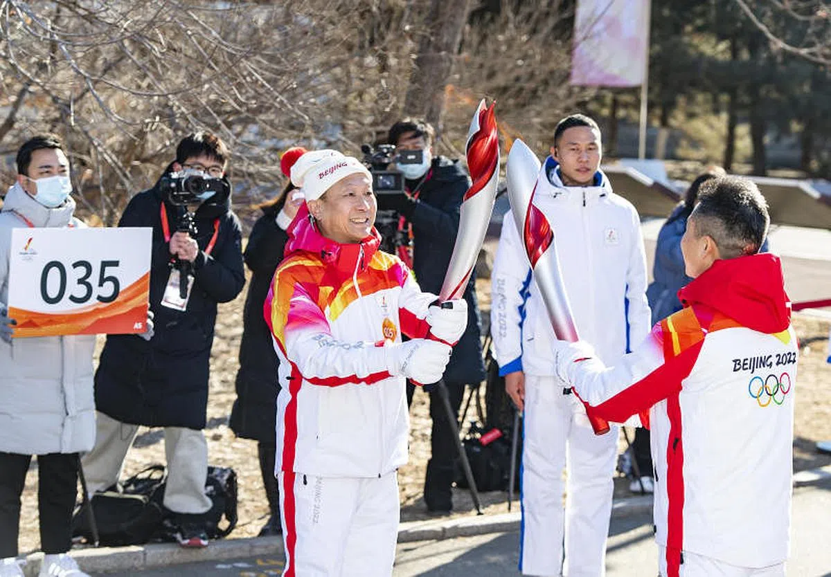 第35棒火炬手陈季华（前左）与第34棒火炬手汪圣军进行接力。（中新社）