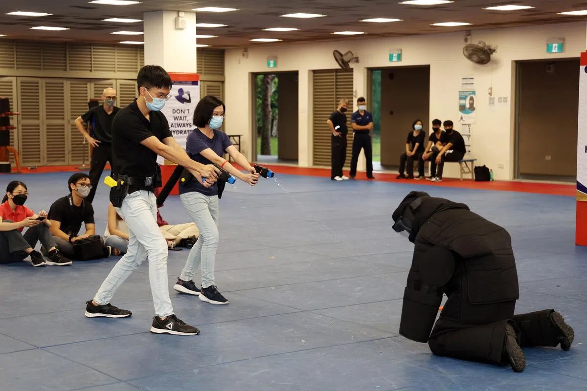 活动现场也同时演练各种罪案情景，当时两名记者使用泰瑟电击枪制伏包裹着黑防护套的“嫌犯”。（王彦燕摄）