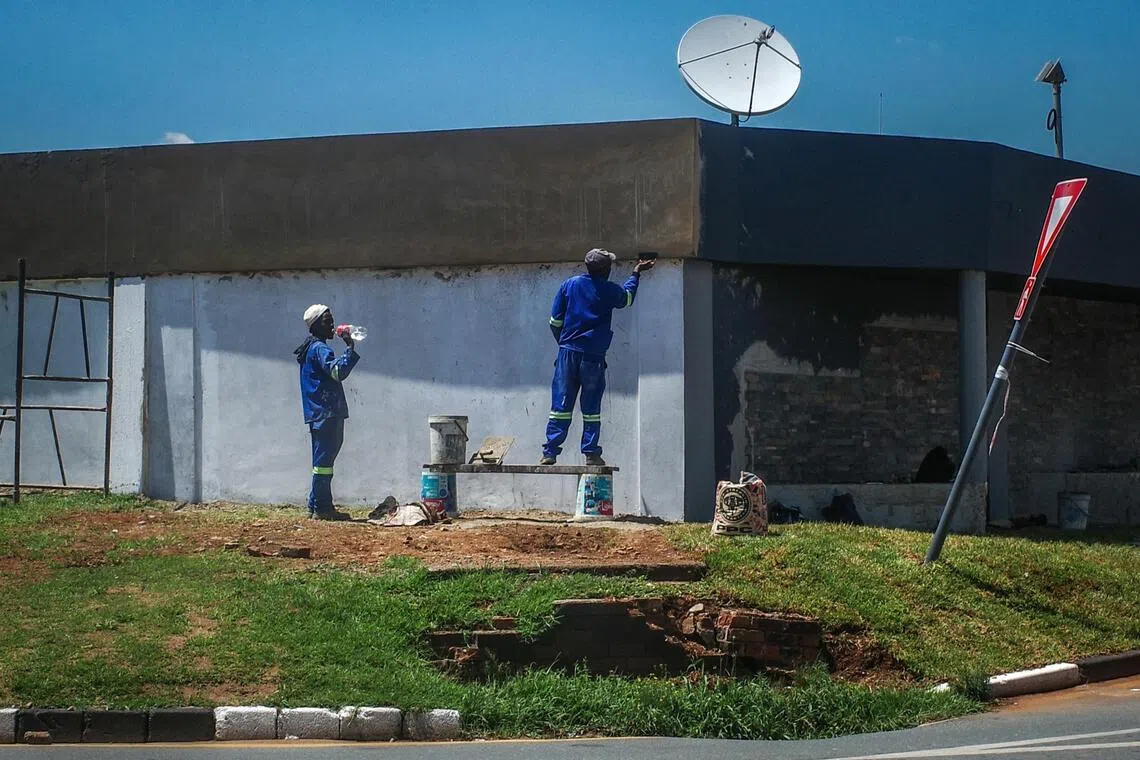 阳光灼烤着油漆工人的脊梁，汗水浸透他们的蓝色工装。（叶振忠摄）