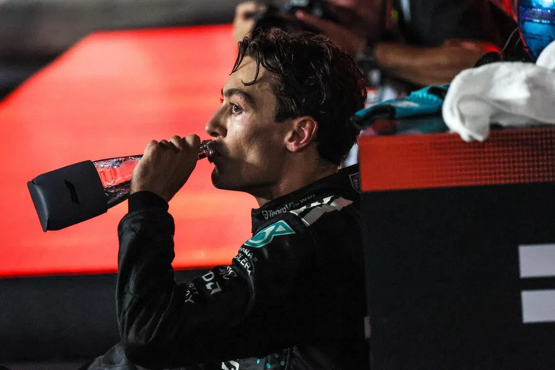 经历新加坡高温和高湿度的“洗礼”后，马赛地车手拉塞尔在赛后坐在地上补水休息。（张俊杰摄）