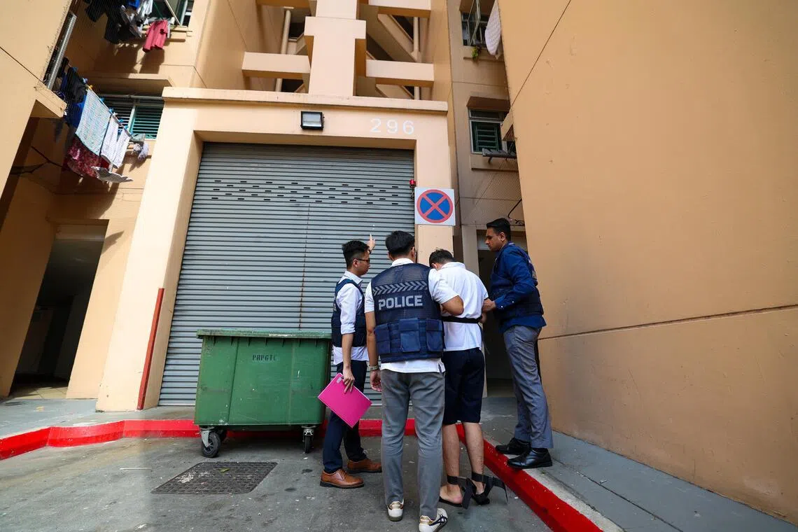 被告被押到组屋垃圾站前问话。一般相信，警车就是停在这里时，遭被告从楼上丢下的鸡蛋砸中。（林明顺摄）