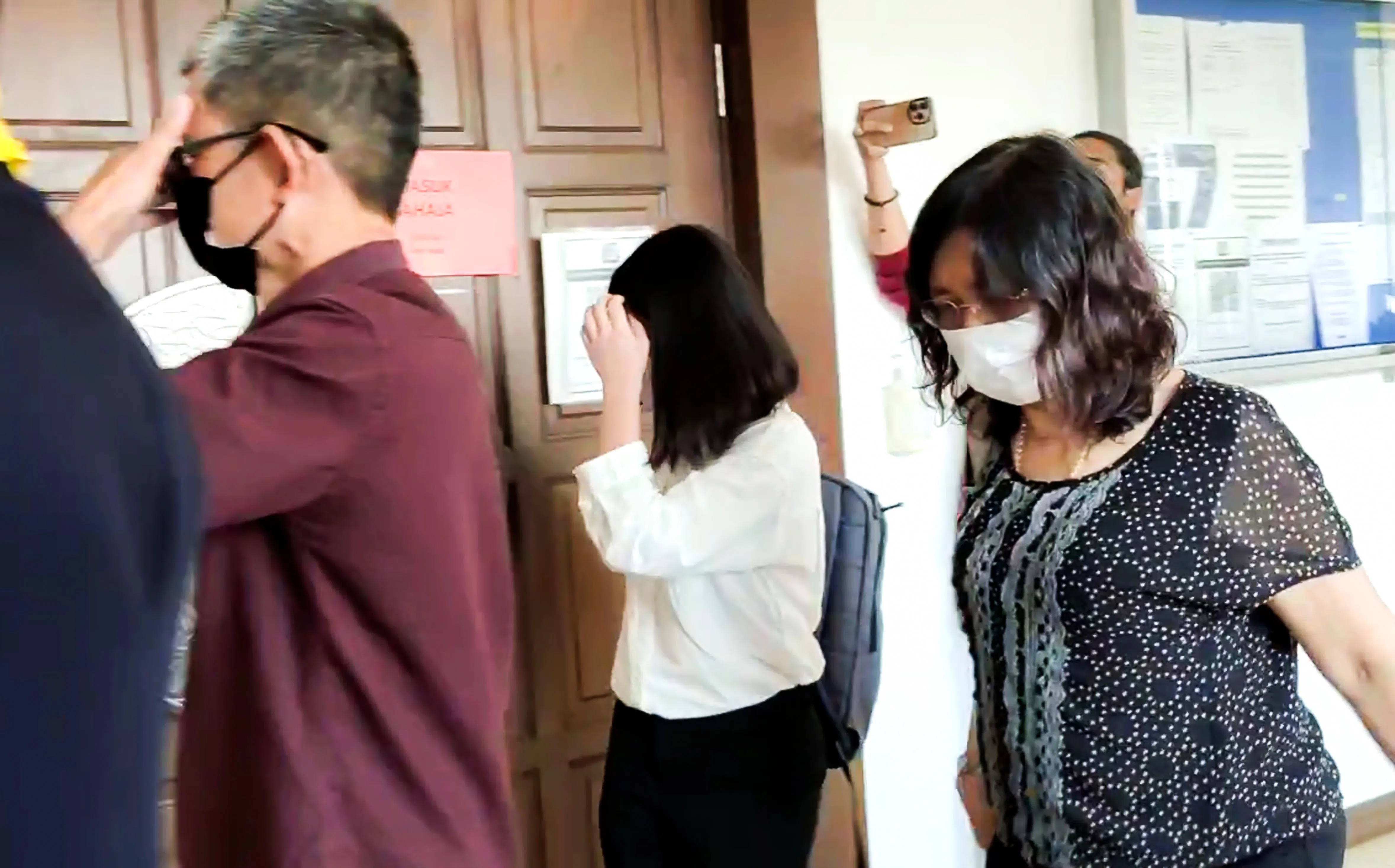 袜子供应商新建昌公司老板苏进发（左起）、女儿苏慧珊及妻子吴丽慧抵达法庭面控时，低头躲避镜头。（ 星洲日报）