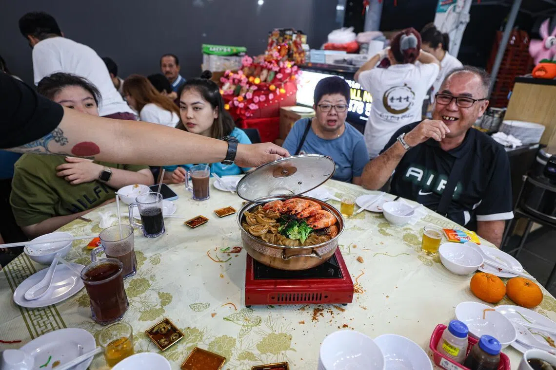 黄良忠（右一，65岁）说，他和太太冯瑞玲（右二，62岁）提早在腊月二十八与岳家聚餐，二十九再和自己的家人团聚。除夕当天则会再到岳母家享用由岳母亲自准备的团圆饭。他说，虽然家里没有吃盆菜的传统，但套餐上有，一家人就顺势尝尝。（关俊威摄）