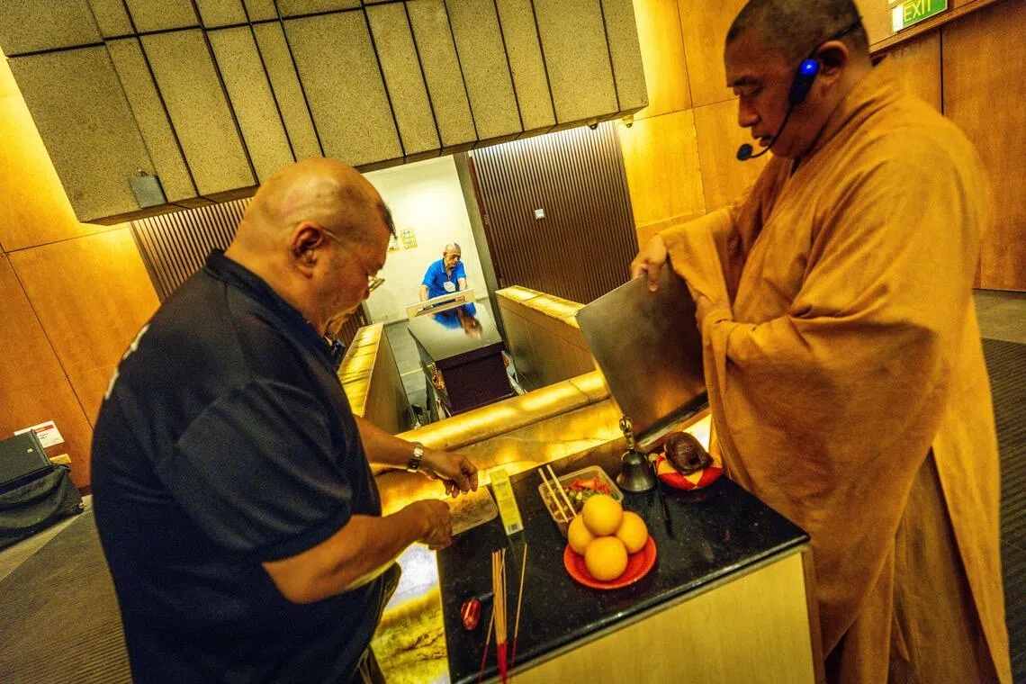 俞肇斌和法师忙着布置简单的灵堂，因无逝者遗照，所以移走相框。（叶振忠摄）