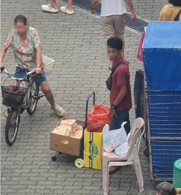 其中一名身穿深红色上衣的男子站在推车前，车上摆放着装有咖喱角的纸箱。（取自STOMP）