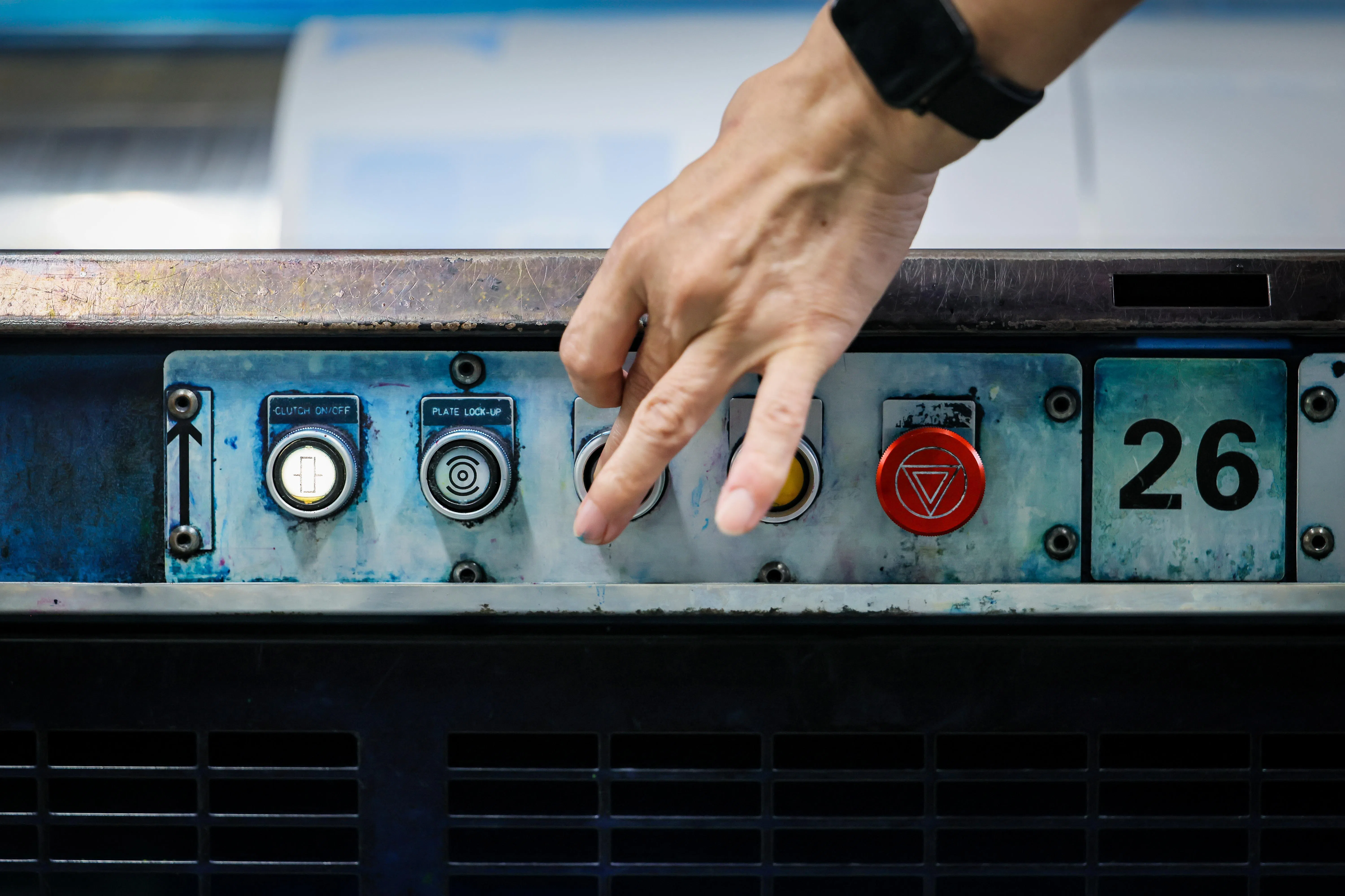 在印刷厂服务超过30年的老员工，熟练地操作按钮，调整印刷机上的铝板。（龙国雄摄）