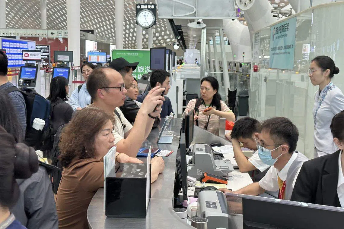 不少受影响游客在深圳宝安机场的服务柜台，尝试为延误或被取消的航班进行改签。（林煇智摄）